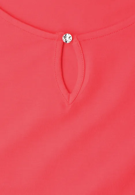 Rood topje met kleine druppelvormige opening en sierlijke knoop