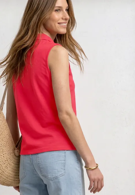 Zijaanzicht van een vrouw in een rood mouwloos shirt, lichte jeans en strooien tas voor witte achtergrond.