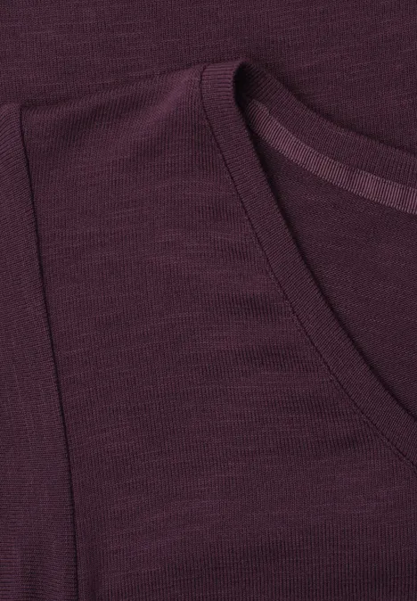 Nahaufnahme eines dunkelvioletten T-Shirts mit Rundhalsausschnitt und erkennbarer Schulternaht.
