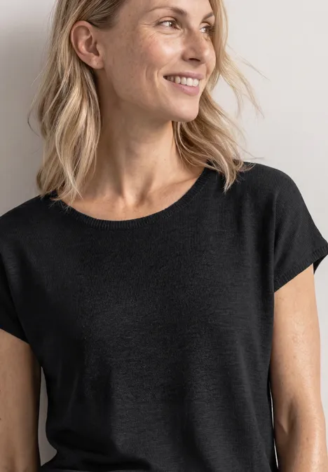 Dropped Shoulder Shirt mit Rundhals Black Nahaufnahme einer Frau ab Brusthöhe in schlichtem schwarzen T-Shirt, schulterlanges blondes Haar.