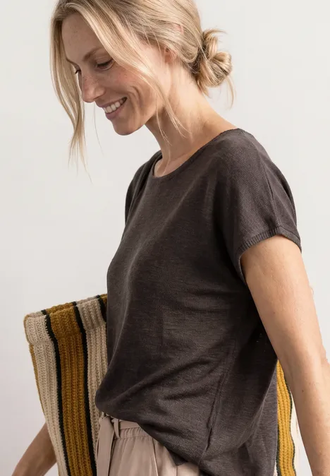 Dropped Shoulder Shirt mit Rundhals espresso brown Frau in lockerem, dunkelbraunem T-Shirt und beigen Jogginghosen vor hellem Hintergrund.