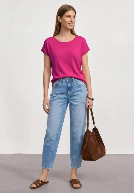 Dropped Shoulder Shirt mit Rundhals magenta dream Frau in pinkem T-Shirt, blauen Jeans, brauner Tasche und Sandalen vor neutralem Hintergrund.