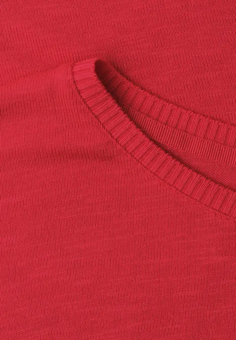 Close-up van een rood kledingstuk met een geribbelde ronde hals.