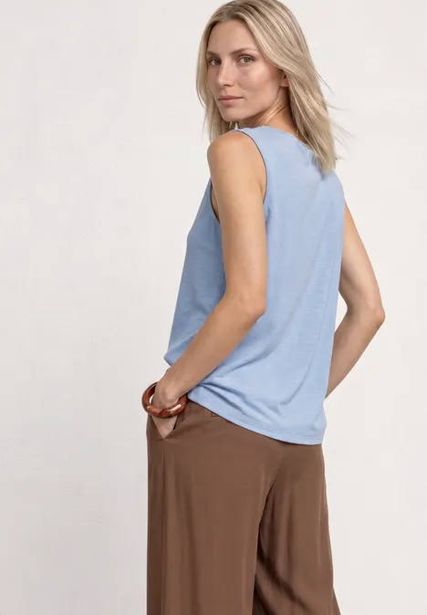 Silk-Look Top mit Wasserfall-Ausschnitt cashmere blue Eine Person in ärmellosem hellblauem Top und brauner Hose, seitlich stehend.