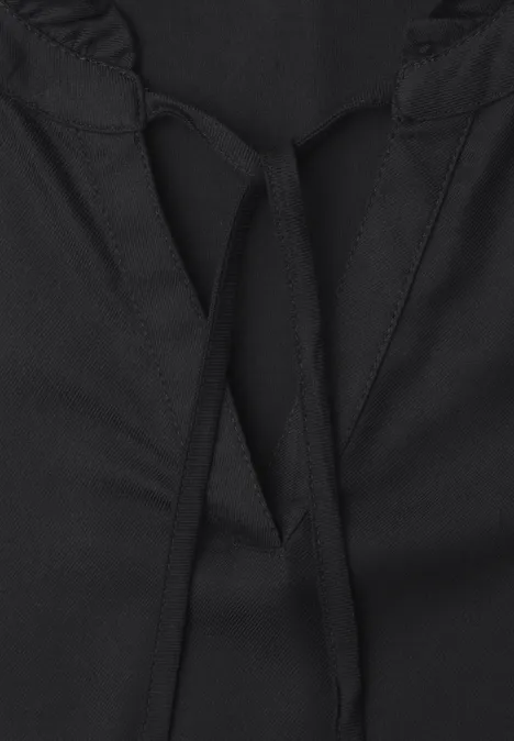 Close-up van een zwart kledingstuk met een diepe V-hals en een trekkoord.