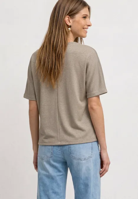 Rückenansicht einer Frau in beigem T-Shirt und blauen Jeans.