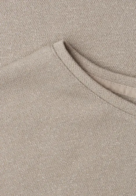 Ein beiges T-Shirt-Ausschnittdetail aus weichem, strukturiertem Stoff.
