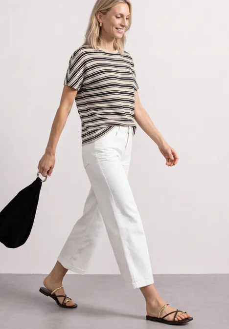 T-shirt en tricot avec col rond Black Frau in gestreiftem T-Shirt, weißen Culottes und schwarzen Sandaletten trägt schwarze Tasche.