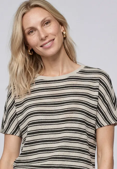 T-shirt en tricot avec col rond Black Frau trägt kurzärmliges gestreiftes Oberteil in Schwarz und Weiß.