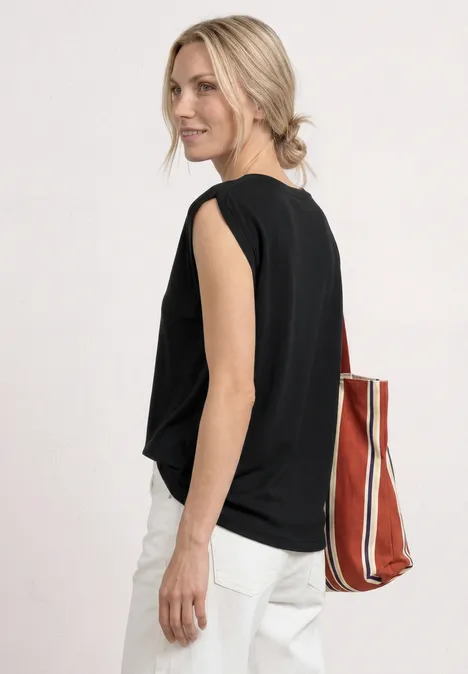 Dropped Shoulder Shirt mit Raffung Black Frau von hinten in schwarzem Top, weißer Hose und blondem Dutt, mit gestreifter Tasche.