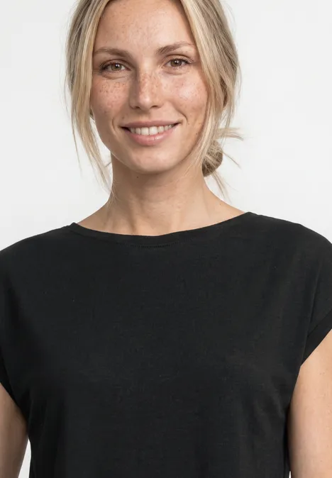 Dropped Shoulder Shirt mit Raffung Black Eine Person mit verpixeltem Gesicht trägt ein schwarzes Shirt vor hellem Hintergrund.