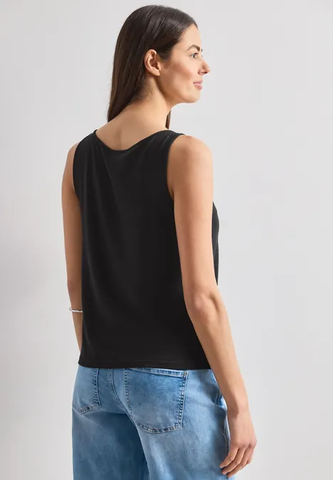 Frau von hinten in schwarzem Top und Jeans.