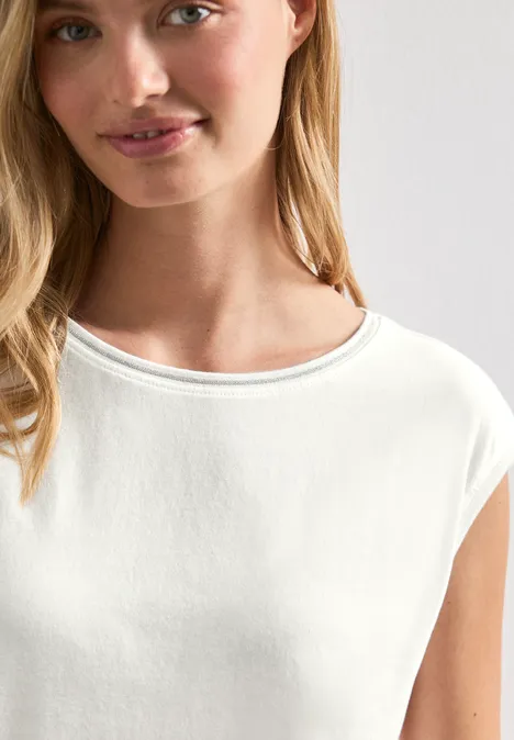 Eine Frau trägt ein schlichtes weißes T-Shirt mit Rundhalsausschnitt.