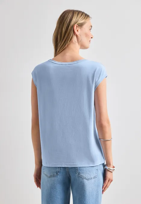 Shirt mit Rundhals und Rippdetails cashmere blue Eine Frau steht mit dem Rücken zur Kamera, trägt ein hellblaues T-Shirt und Jeans.