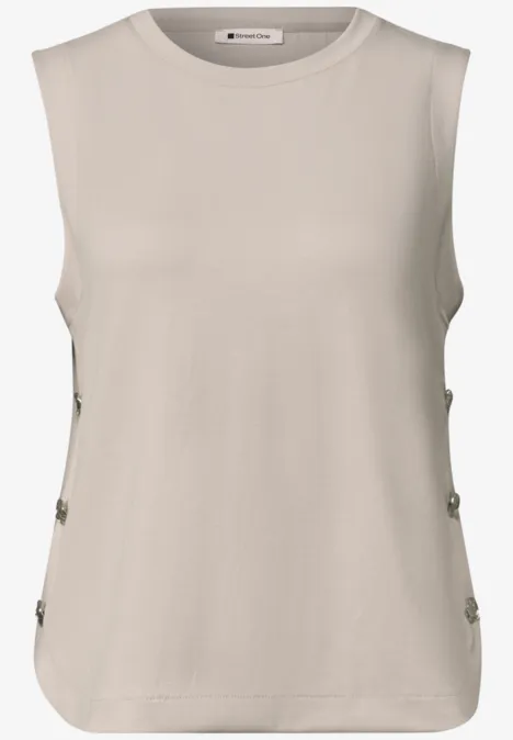 Mouwloos beige top met ronde hals en knoopsluiting aan de zijkanten.