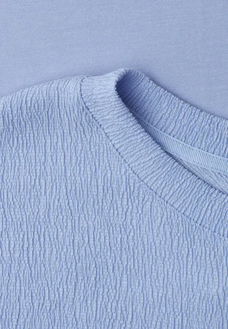 Nahaufnahme eines hellblauen Shirts mit strukturiertem Stoff und Rundhalsausschnitt.