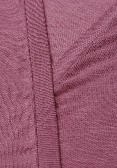 Gros plan sur un tissu rose à texture fine avec une couture apparente.