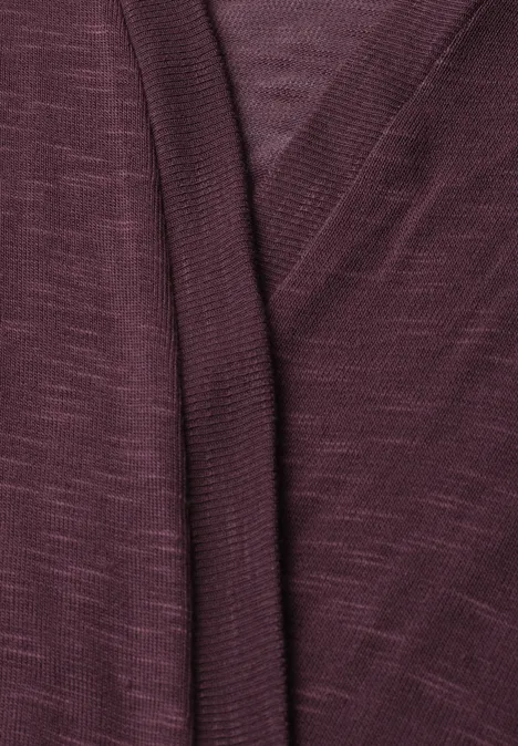 Nahaufnahme eines burgunderroten Strickcardigans mit überlappendem V-Ausschnitt.