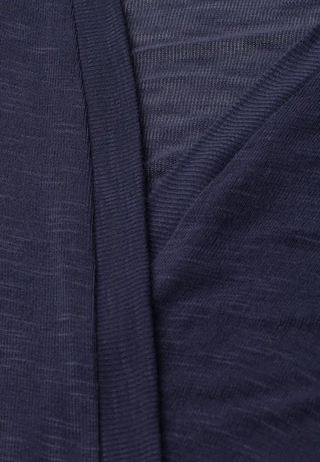 Nahaufnahme eines dunkelblauen, dünnen Strickstoffs mit dekorativer Überlappung am Saum.