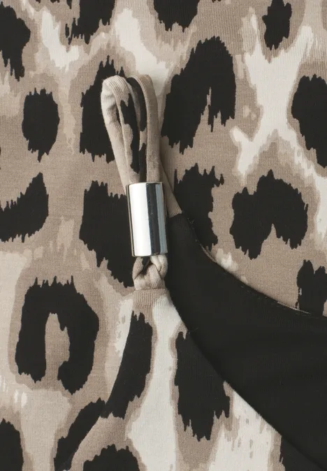 Gros plan d'un tissu imprimé léopard à côté d'un tissu noir et d'une boucle métallique argentée sur une sangle.