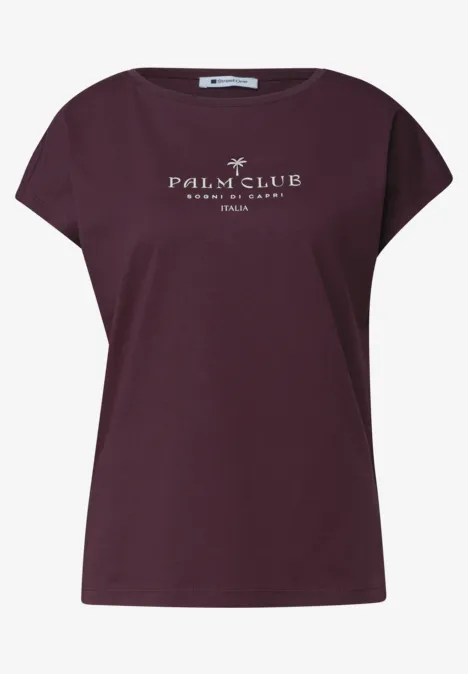 Dropped Shoulder Shirt mit Wording rustic rouge Weinrotes Damen-T-Shirt mit überschnittenen Ärmeln und weißem Palm Club-Print vorne.