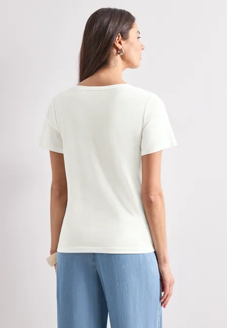 Rückenansicht einer Frau im weißen T-Shirt und hellblauer Hose vor neutralem Hintergrund.
