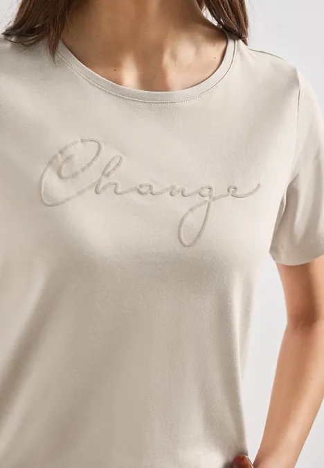 Beige dames-T-shirt met de sierlijke tekst 'Change' in cursief.