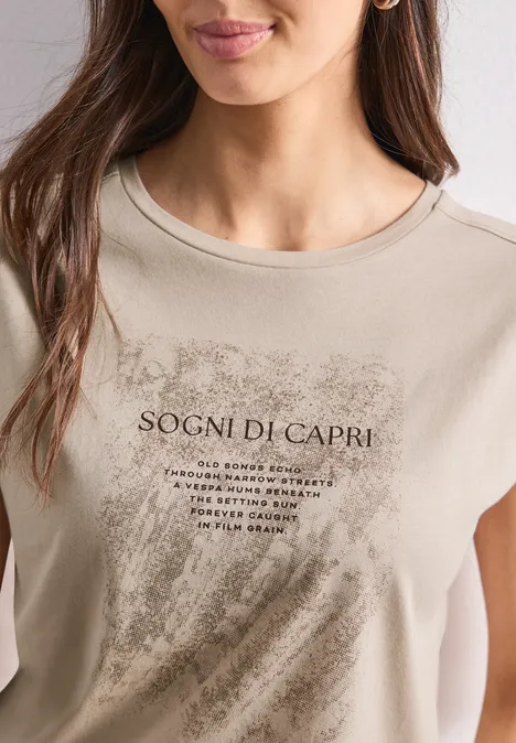Beige T-shirt gedragen door een vrouw met 'Sogni di Capri'-opdruk en penseelstreekpatroon.
