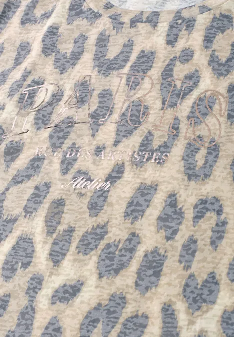 Gros plan sur un tissu beige à taches léopard gris avec lettrage blanc 'Divis Studio Atelier'.