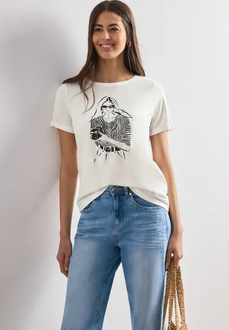 Frau in weißem T-Shirt mit Aufdruck, blauen Jeans und Schultertasche.
