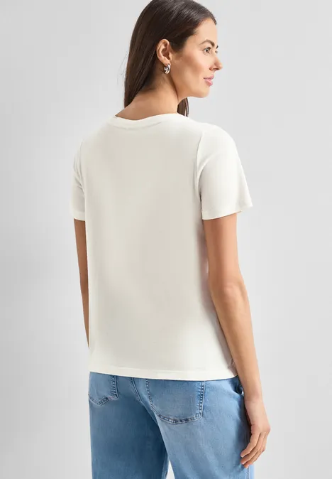 Frau von hinten in weißem T-Shirt und blauer Jeans.