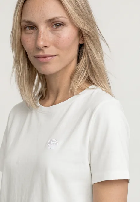 Koszulka z okrągłym dekoltem i haftowanymi detalami off white Kobieta w białym t-shircie na neutralnym tle.