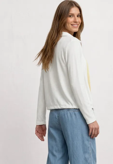 Leichte Langam Jacke in Leinen-Optik off white Frau von der Seite in weißer, leichter Jacke mit langen Ärmeln und blauen Jeans.