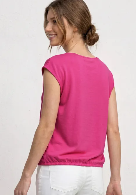 Dropped Shoulder Shirt mit U-Boot-Ausschnitt magenta dream Eine Frau mit hochgestecktem Haar trägt rosa Top und weiße Hose, Rückenansicht vor hellem Hintergrund.