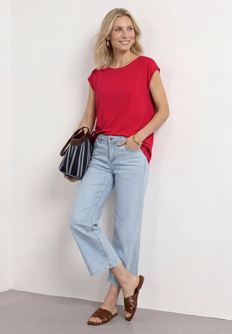 Dropped Shoulder Shirt mit U-Boot-Ausschnitt salsa red Frau in rotem T-Shirt, hellblauen Jeans und braunen Sandalen trägt eine gestreifte Handtasche.
