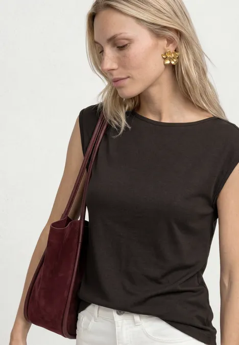 Basic Shirt mit U-Boot-Ausschnitt espresso brown Blonde Frau in schwarzem Tanktop, weißer Hose, goldenen Ohrringen und burgunderfarbener Tasche.