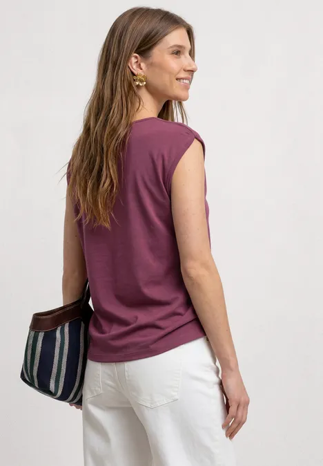 Basic Shirt mit U-Boot-Ausschnitt dark clouded blush Eine Frau in einem ärmellosen lila Top und weißen Hosen mit gestreifter Tasche, Rückenansicht.
