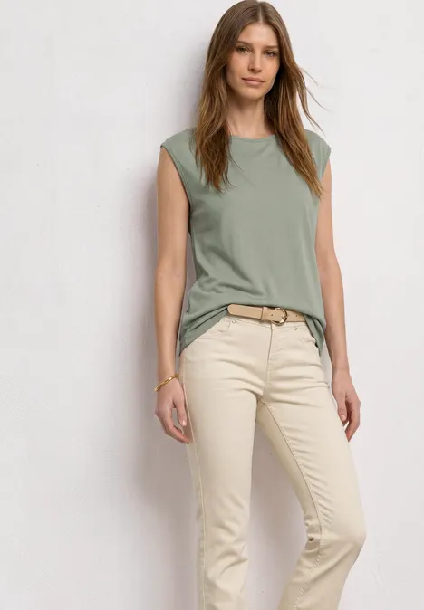 Basic Shirt mit U-Boot-Ausschnitt mint leaf Frau in hellgrünem ärmellosem Oberteil und beigen Hosen vor weißem Hintergrund.