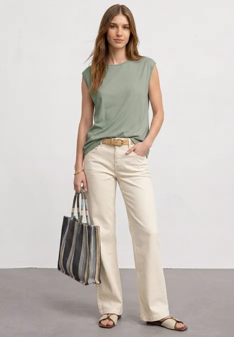 Basic Shirt mit U-Boot-Ausschnitt mint leaf Eine Frau in grünem ärmellosem Top, hellen Hose und Sandalen mit gestreifter Handtasche.