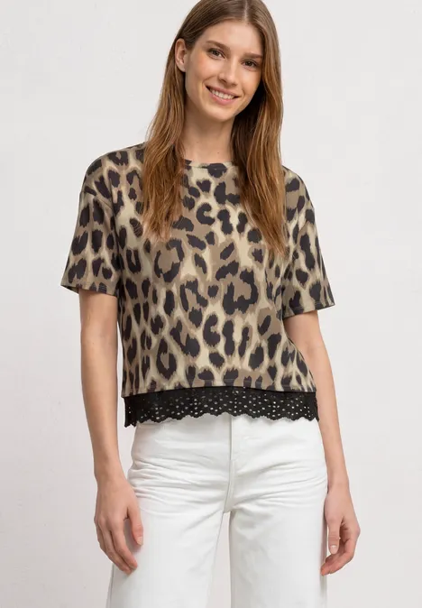Vrouw draagt een beige-zwarte luipaardprint t-shirt met kanten zoom en witte broek.