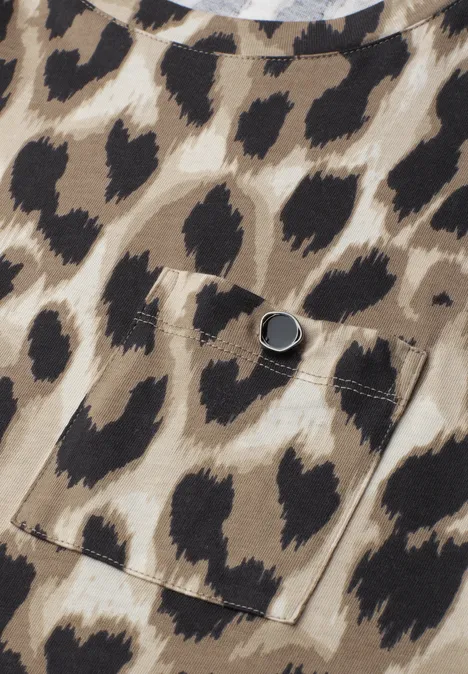 Naheansicht einer Tasche an einem Stoff mit braun-beigen Leopardenmuster und Druckknopf.