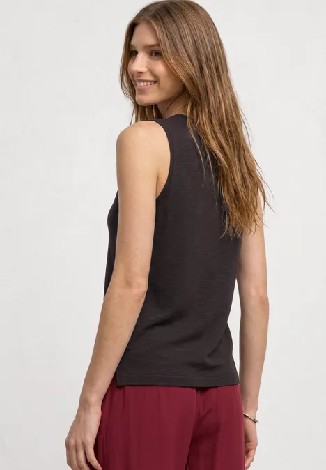 Frau von hinten in schwarzem Tanktop und roter Hose vor hellem Hintergrund.