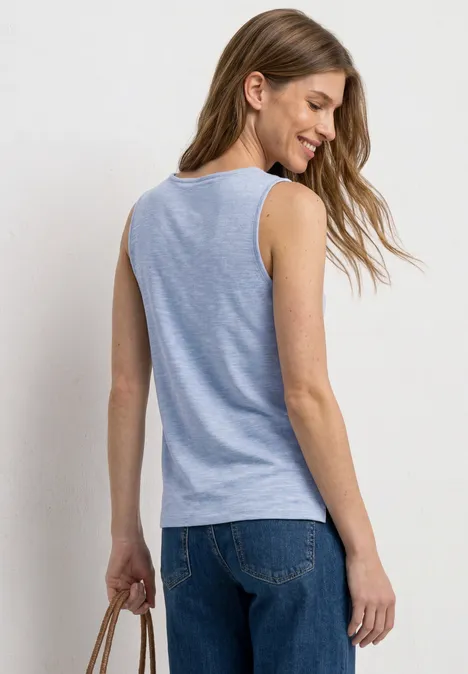 Frau von hinten in hellblauem ärmellosem Top und Jeans, hält eine braune Tasche.