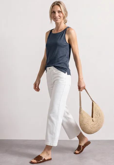 Top mit U-Boot-Ausschnitt und Schulterdetail ashen blue Frau in weißer, weiter Hose, blauem ärmellosem Top, braunen Sandalen und runder Basttasche.