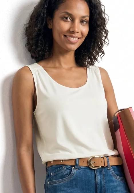 Top aus Jersey mit Elastiksaum off white Frau in weißem Tanktop und Jeans hält bunte Ordner an der Hüfte.