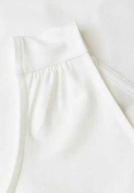Top aus Jersey mit Elastiksaum off white Nahaufnahme eines weißen Tops mit breitem Träger und feinen Stofffalten am Schulterbereich.