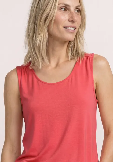 Frau mit blonden Haaren trägt rotes ärmelloses Top.