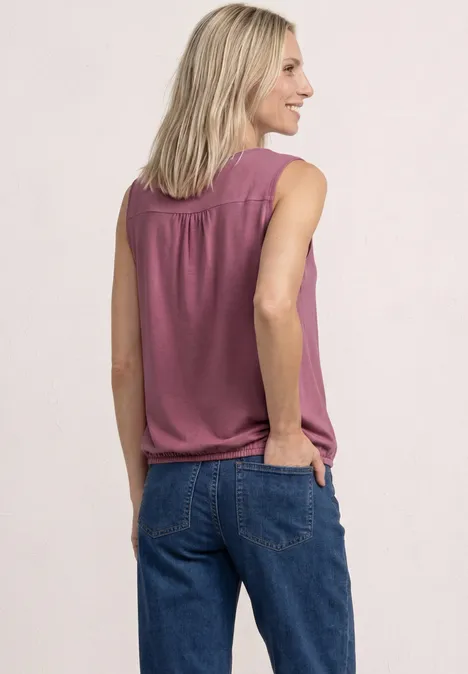 Top aus Jersey mit Elastiksaum dark clouded blush Frau von hinten in ärmelloser rosafarbener Bluse und blauen Jeans, eine Hand in der Tasche.