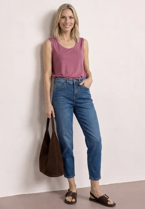 Top aus Jersey mit Elastiksaum dark clouded blush Frau in rosa Top und blauen Jeans, trägt dunkle Tasche und Sandalen, steht vor heller Wand.