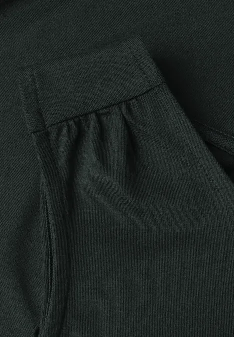 Nahaufnahme eines dunkelgrünen Kleidungsstücks mit sichtbarer Naht, Falte und kleiner Tasche
